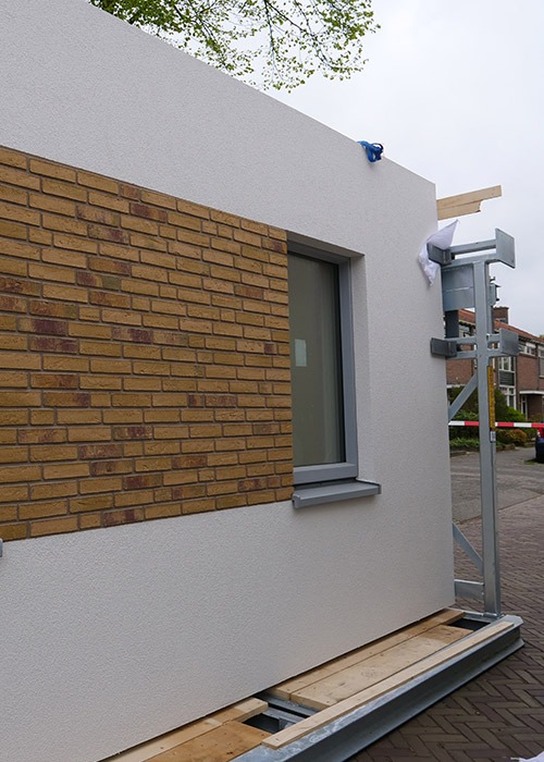 De stalen frames werden met isolatieplaten van Sto voorzien en in het atelier verder afgewerkt met een combinatie van steenstrips en crepi. Deze modules werden in hun geheel op de werf geïnstalleerd.